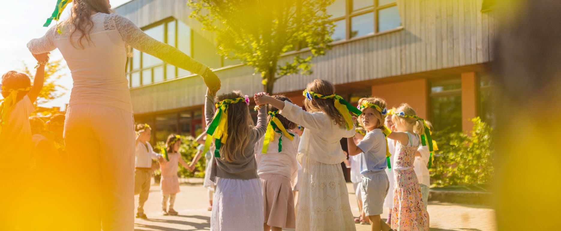 Sfeerbeeld van het schoolplein tijdens Pinksteren op Vrijeschool De Driestroom, met kinderen in een kring, gefotografeerd AVG-proof.