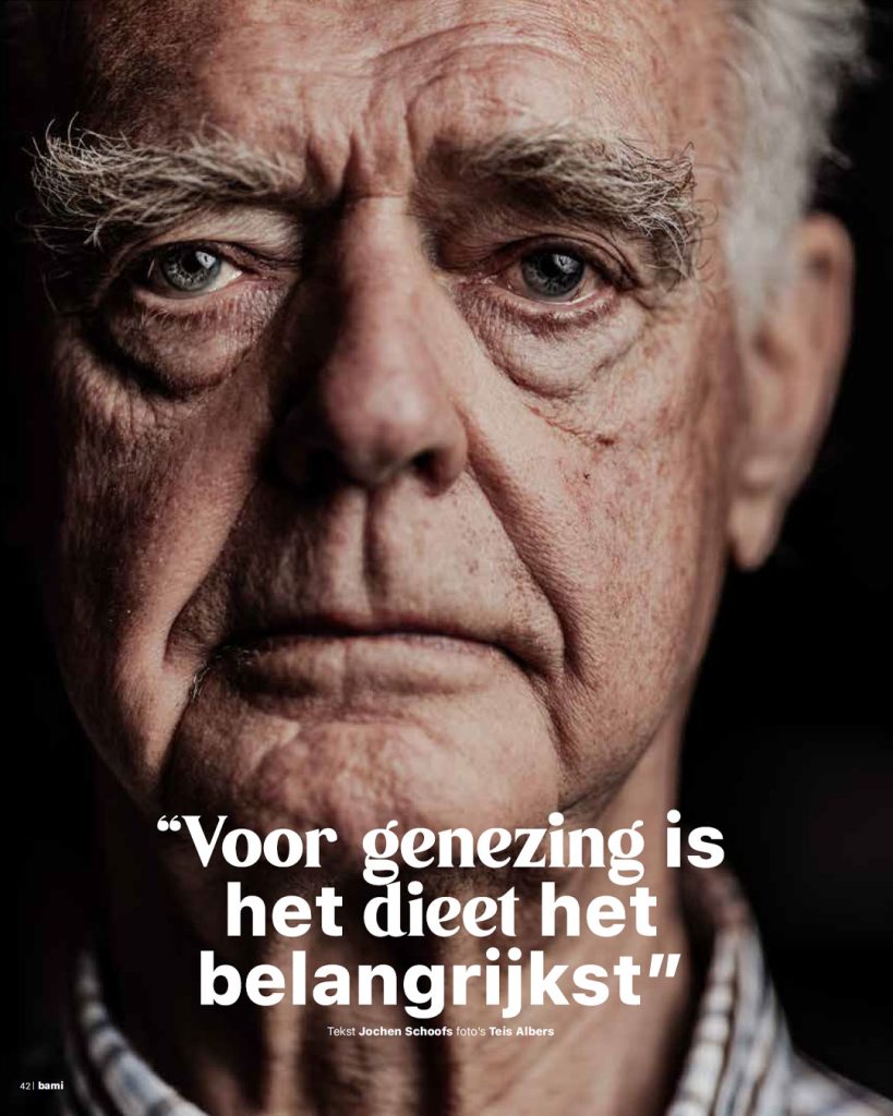 Indringende close-up portretfoto van een oudere man die recht in de camera kijkt. Elke rimpel en detail is zichtbaar tegen een zwarte achtergrond. Gefotografeerd voor een artikel over gezondheid en dieet in dorpsglossy BAMI.