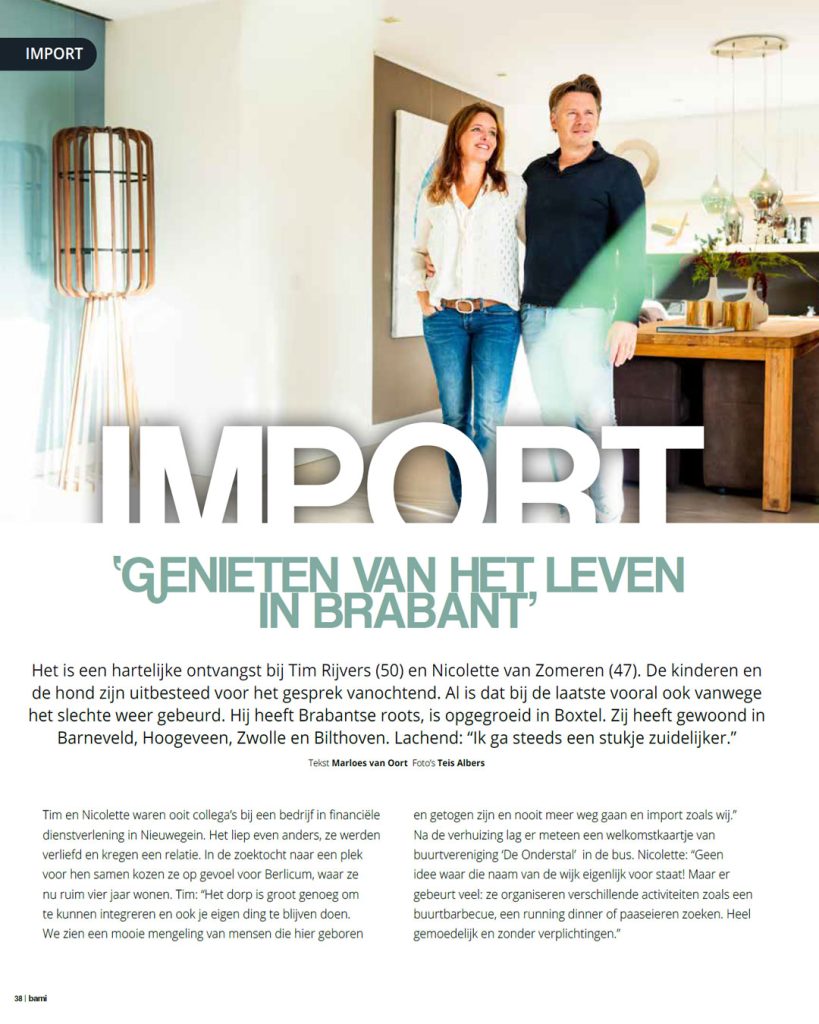 Fris redactioneel portret van een stel (Tim en Nicolette) staand in hun moderne woonkamer met houten tafel en designlampen. Gefotografeerd voor de rubriek 'Import' in dorpsglossy BAMI over verhuizen naar Berlicum.
