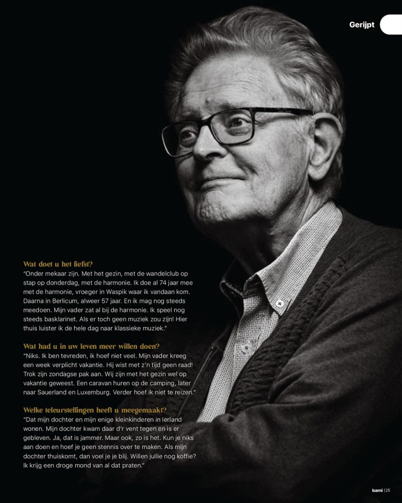 Klassiek zwart-wit portret van een oudere man met bril, zijaanzicht tegen een zwarte achtergrond. De man lacht zachtjes. Redactionele fotografie voor de rubriek 'Gerijpt' in BAMI magazine (Berlicum).
